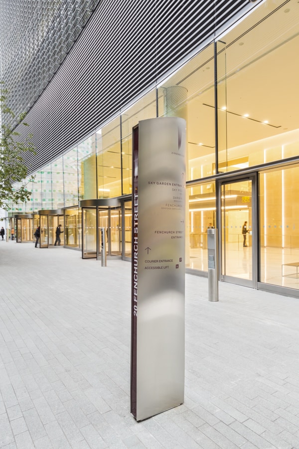 Large curved, stainless-steel totem sign that echoes the shape of the building located in the plaza outside 20 Fenchurch St