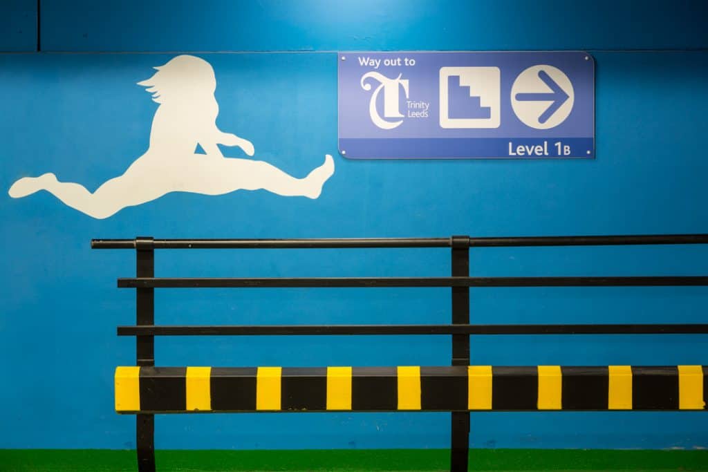 Graffiti style image of a hurdler in mid flight on the wall next to a walkway, plays off the handrail