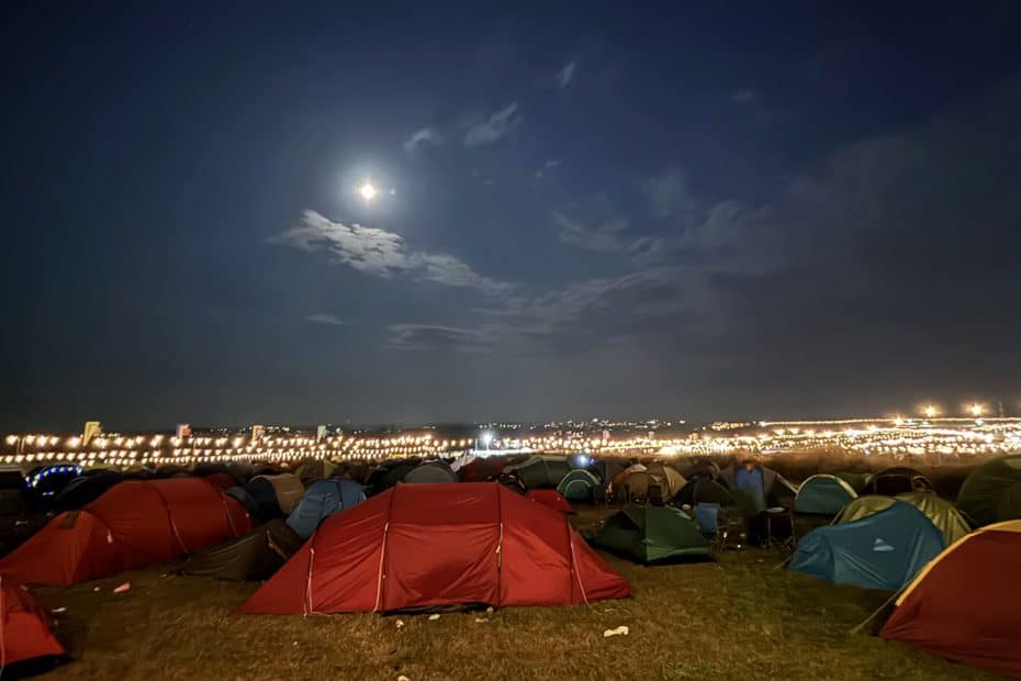 Night-time view across a festival camping site towards the main arena